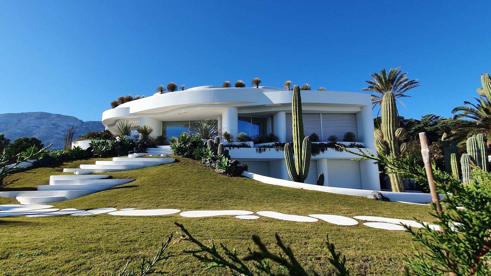 Villa blanche contemporaine sous un soleil intense, grandes ouvertures protégées